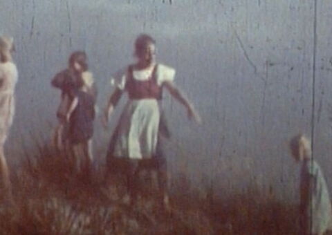 Verblasster historischer Filmstill aus „Das Ungesagte“ mit mehreren Kindern und Frauen in einer offenen, kargen Landschaft.