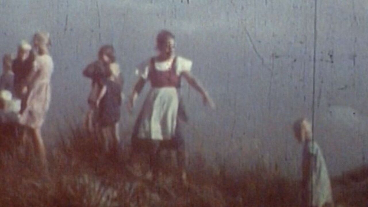 Verblasster historischer Filmstill aus „Das Ungesagte“ mit mehreren Kindern und Frauen in einer offenen, kargen Landschaft.